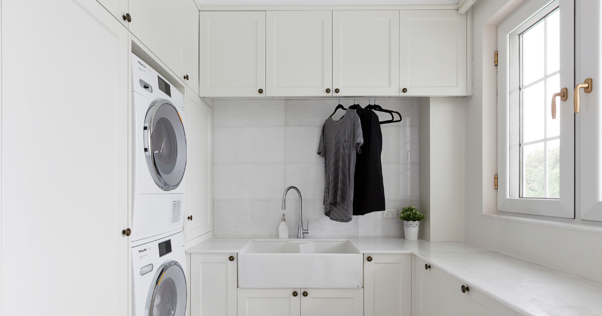 An image of a custom laundry space designed by Creative by Design with two t-shirts hanging on hangers.